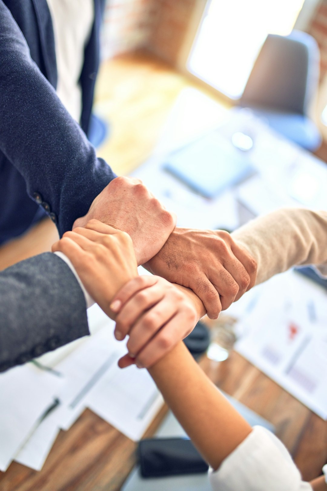 Business professionals interlocking hands in a circle to show teamwork.